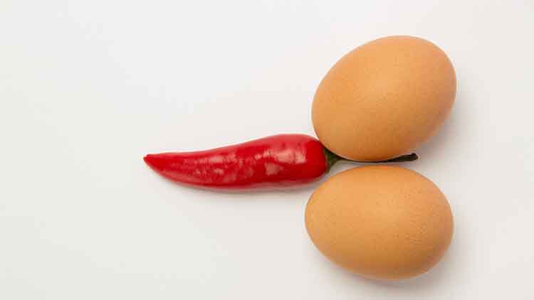 Red hot pepper and two chicken eggs on a white background
