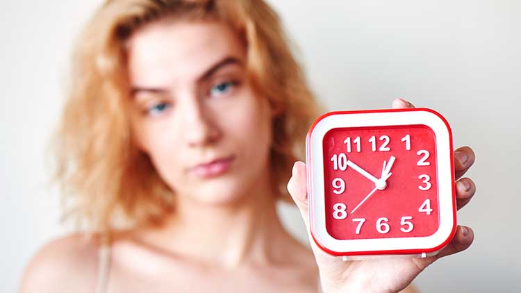 The concept of premature ejaculation men. Girl on a white background holding a red clock closeup