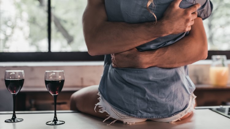 Couple hugging on kitchen side next to wine