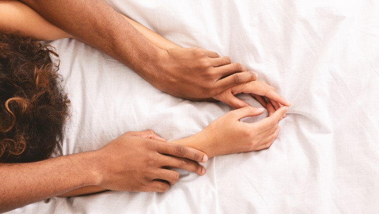 Couple on bed hands grasping arms