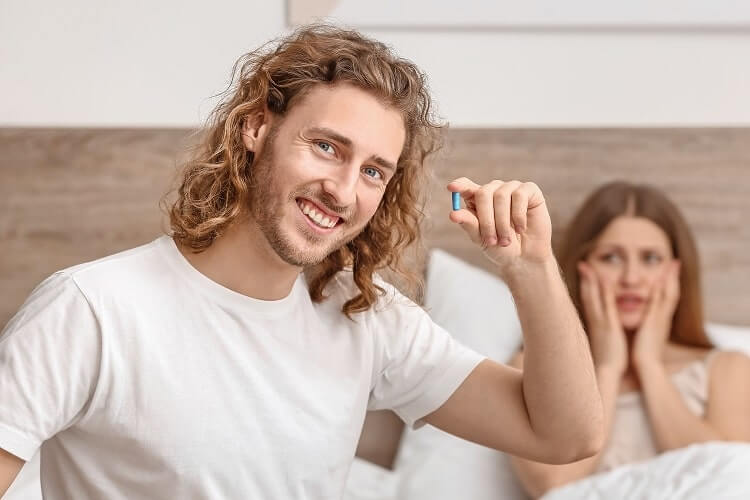 Man with an enhancement pill in a bedroom