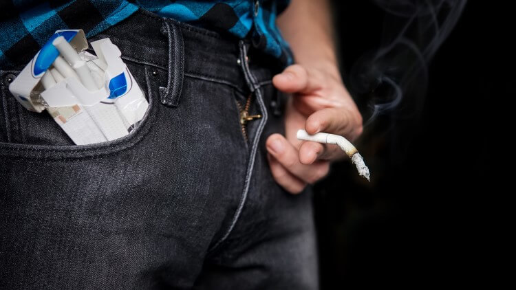 Man holding limp cigarette in front of groin