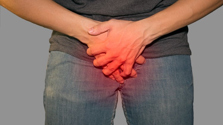 Man holding painful penis through jeans