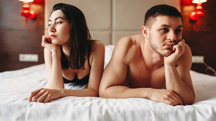 man and a woman laying on the bed together whilst looking away from each other