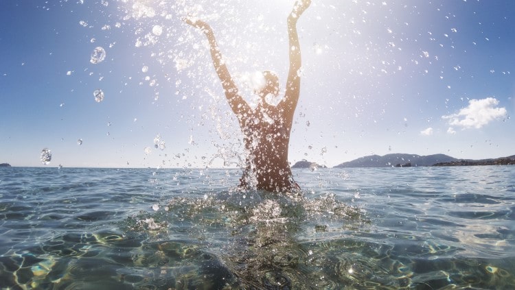 Woman stood in the ocean throwing water into the air